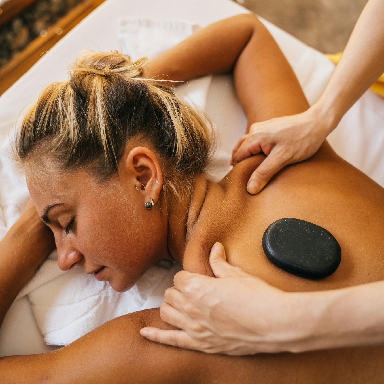Hot-Stone Massage La Calamine Frau erhält eine Rückenmassage mit einem heißen Stein. Entspannung und Wellness.